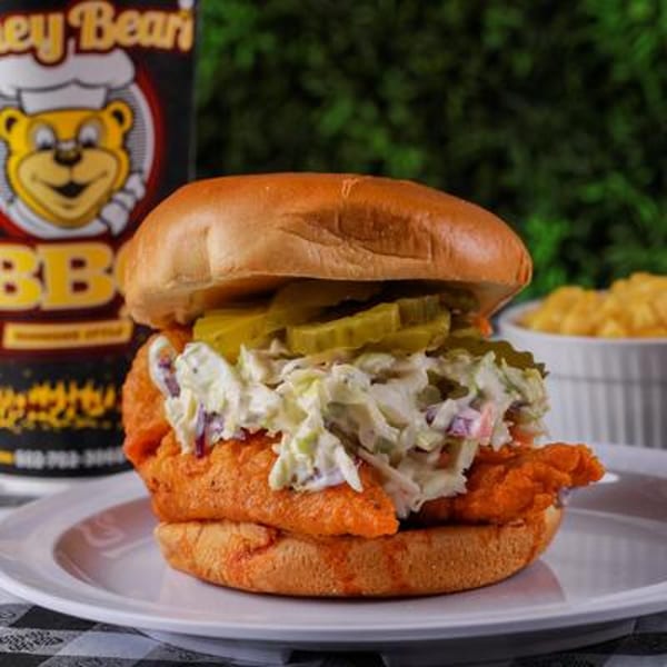 Honey Bear's BBQ fried chicken sandwich with coleslaw and pickles on a bun, with mac and cheese.
