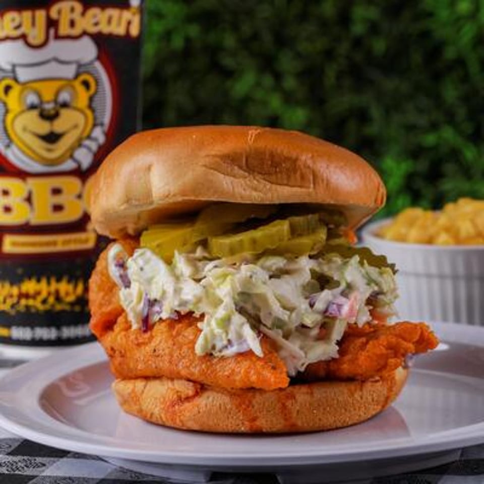 Honey Bear's BBQ fried chicken sandwich with coleslaw and pickles on a bun, with mac and cheese.