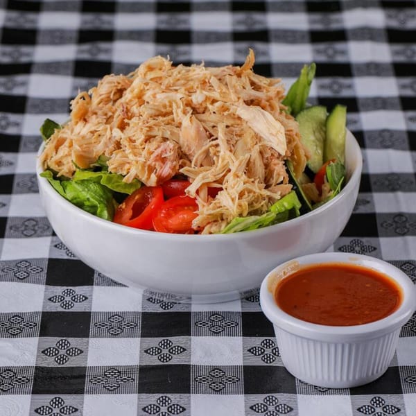 Honey Bear's BBQ pulled chicken salad with lettuce, tomatoes, cucumbers, and a side of dressing.