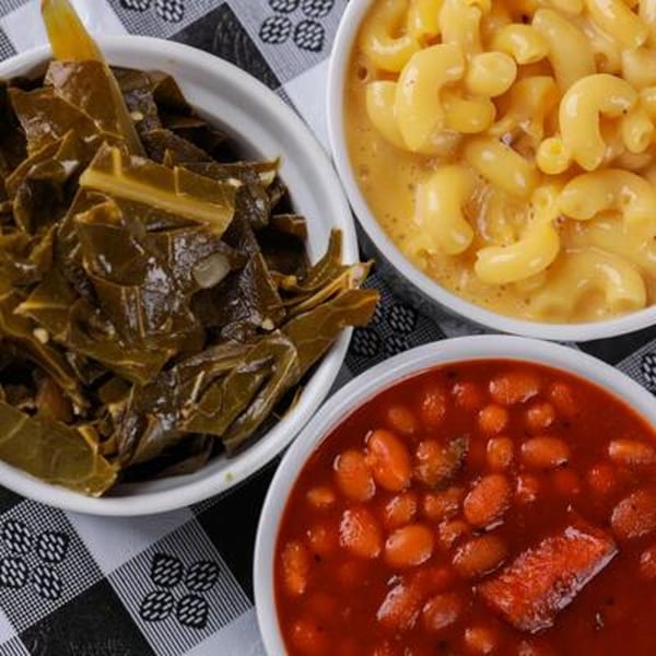 Three bowls of Honey Bear's BBQ sides: collard greens, macaroni and cheese, and baked beans.